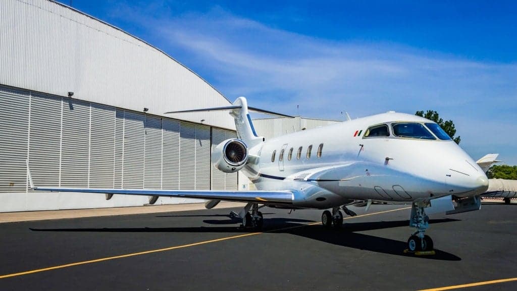 A Bombardier Challenger 300 parked on the tarmac in front of a hangar.