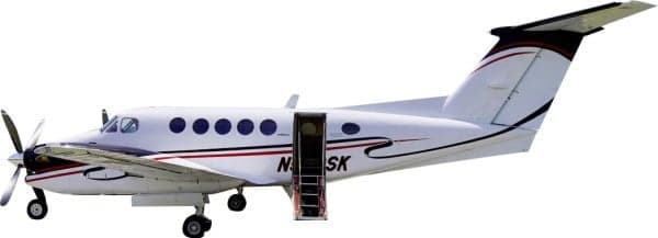 A white Beechcraft King Air with red and black stripes, registration N508SK, on the ground with its airstair door open.
