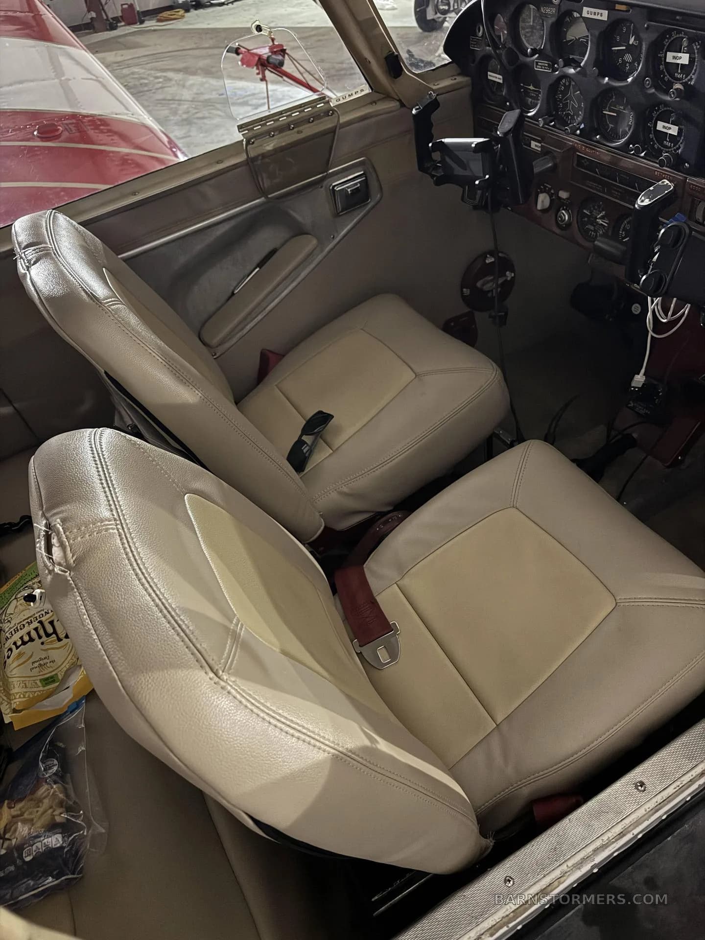 The light beige leather interior seats and a partial view of the instrument panel of a Mooney M20 series aircraft.