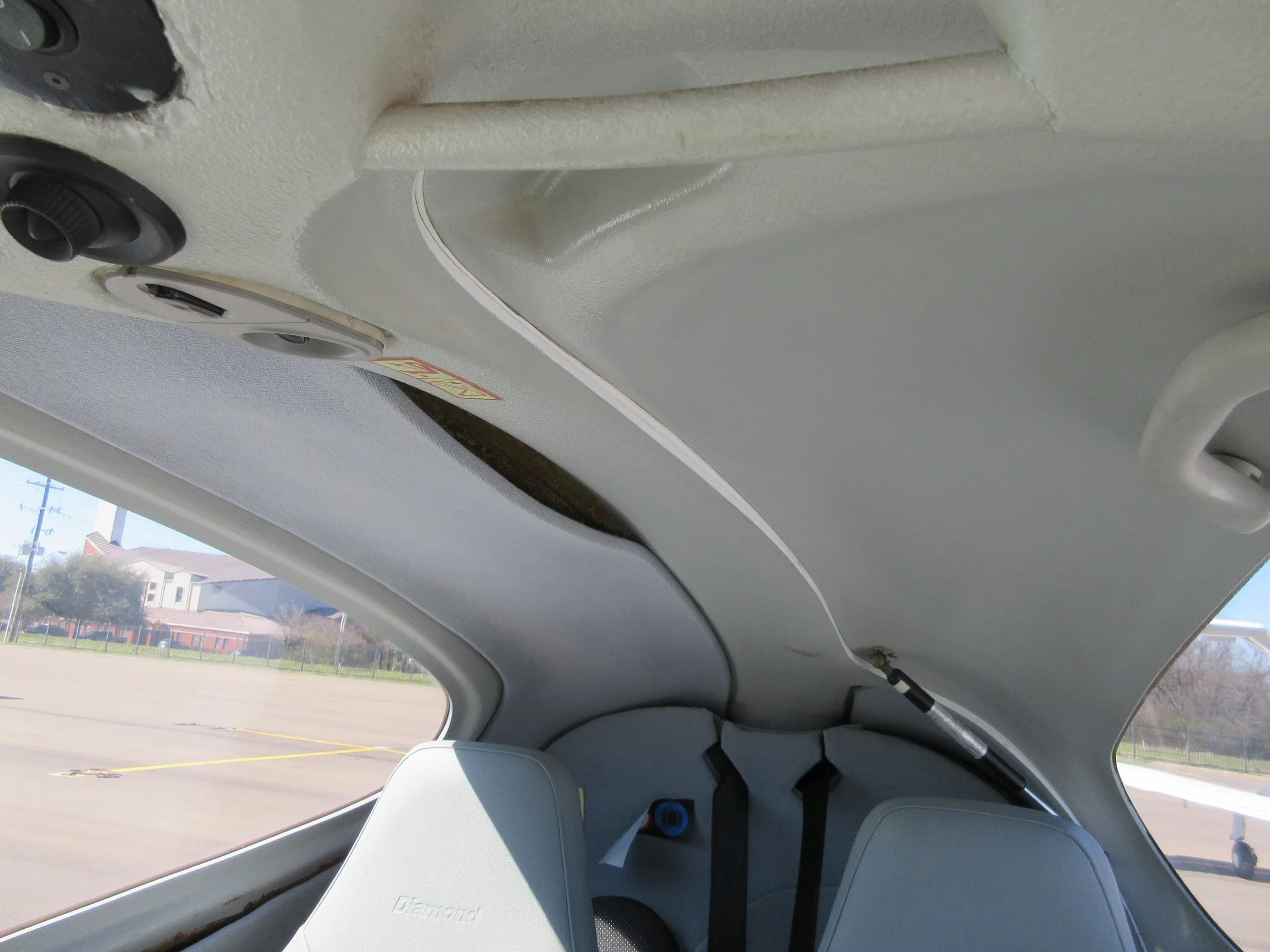 The light gray interior ceiling and upper seats of a Diamond aircraft cabin.