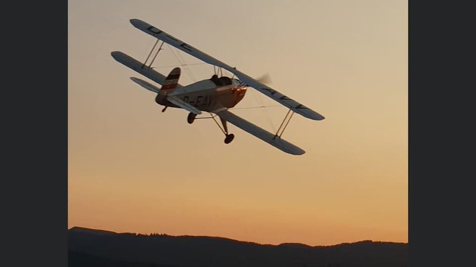 D-EAVV biplane flying with mountains in the background.