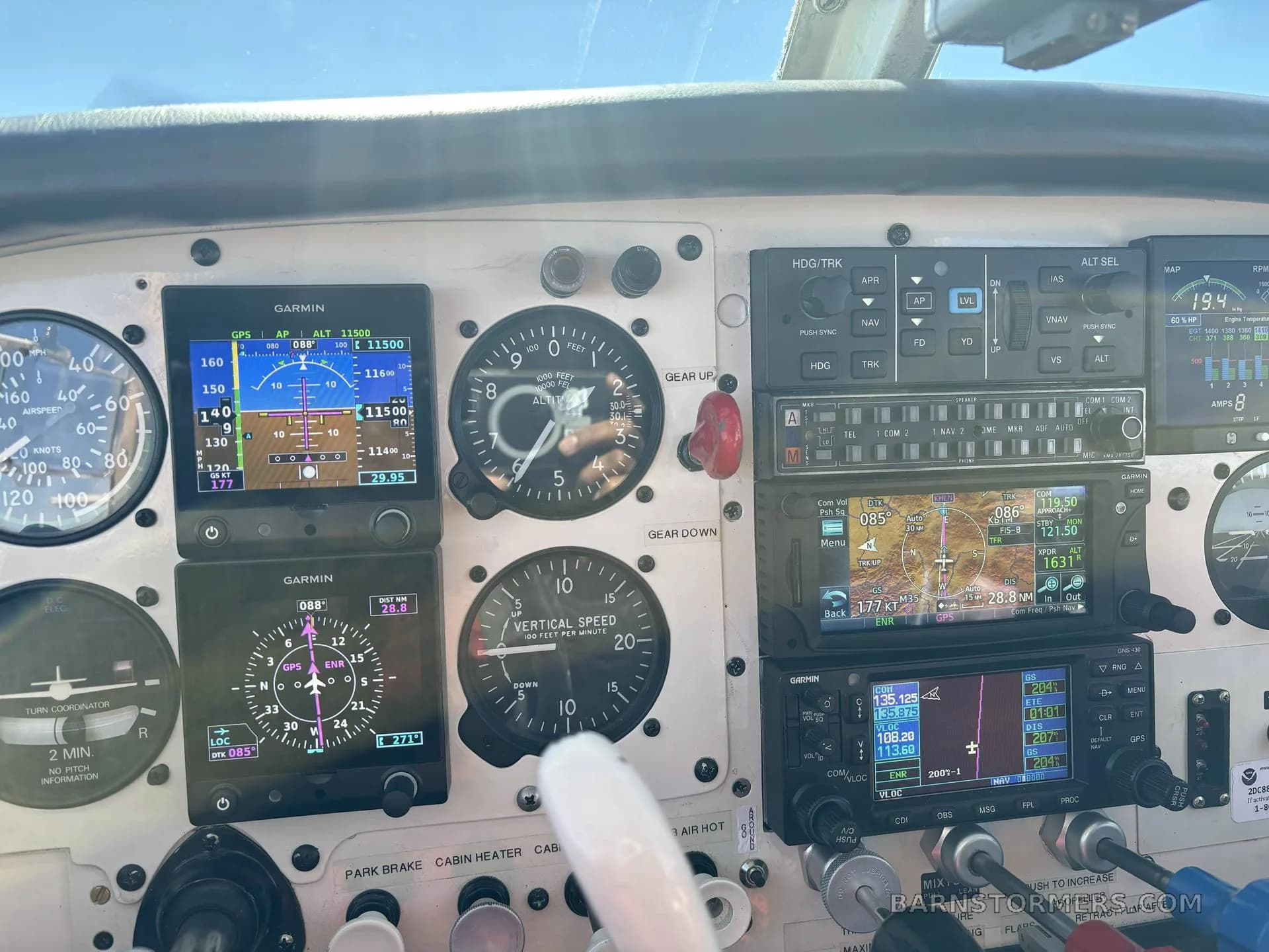 A detailed view of an aircraft cockpit instrument panel featuring multiple Garmin displays and traditional analog gauges.