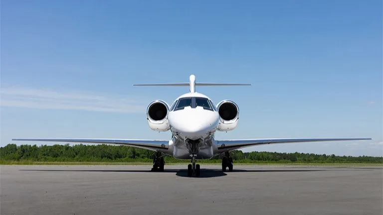 Front view of a white jet aircraft parked on the tarmac.