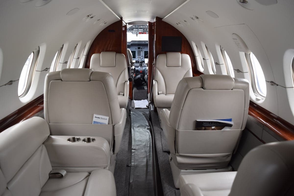 View of the aircraft cabin with cream-colored leather seats and wood trim.