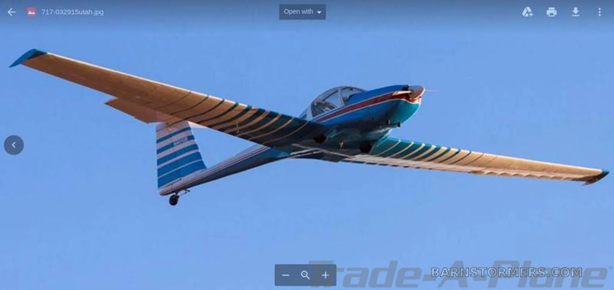 A blue and gold aircraft with a red nose and striped wings, tail number N4012B, flying against a clear blue sky.