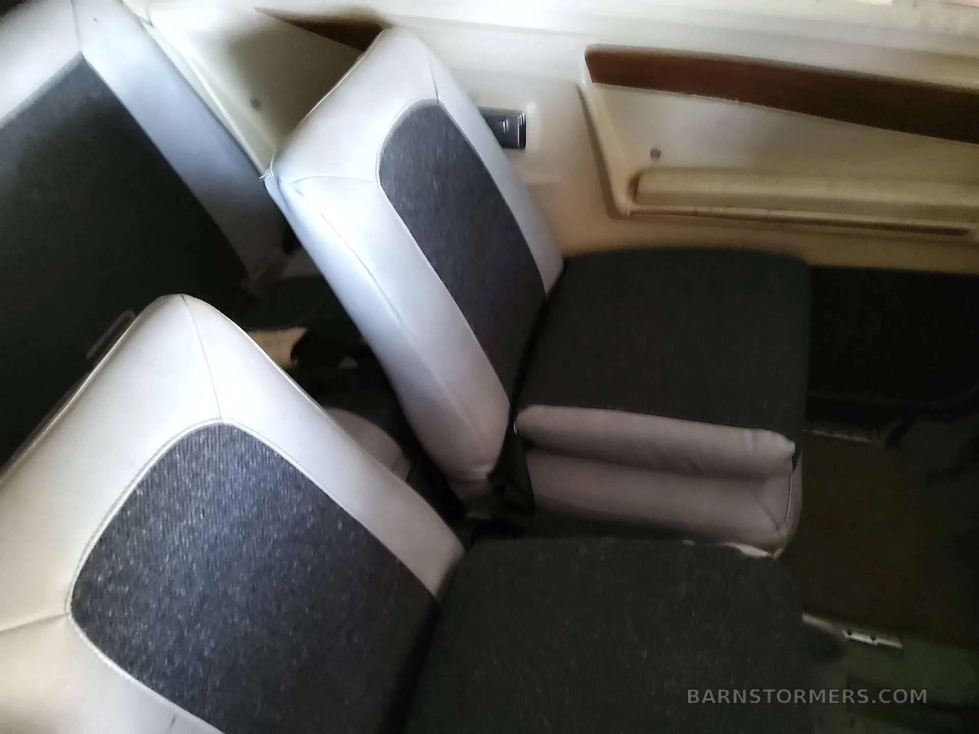 Interior view of the aircraft cabin showing white and dark gray upholstered seats.