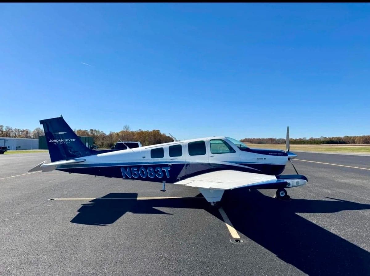 A blue and white Mooney M20J aircraft with tail number N5083T is parked on the tarmac.