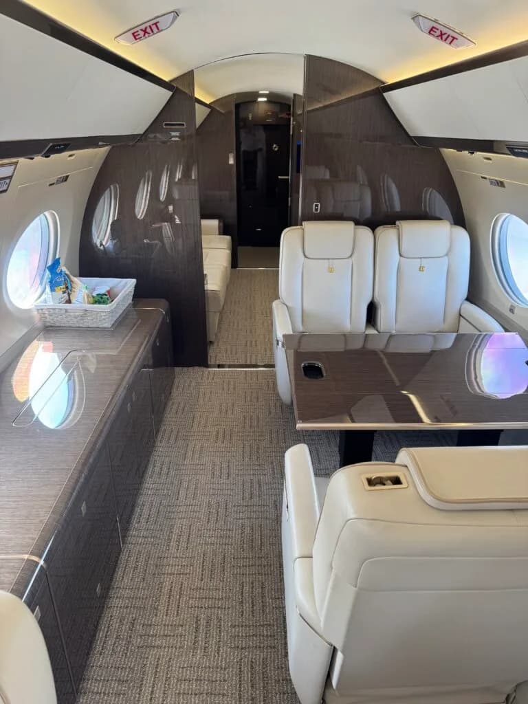 A view of the Gulfstream cabin showing a dining area with a table and seats, and a galley counter with snacks.