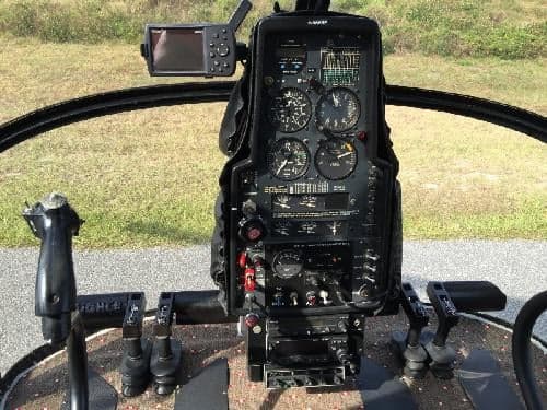 The cockpit of the helicopter features a black instrument panel with various gauges and controls.
