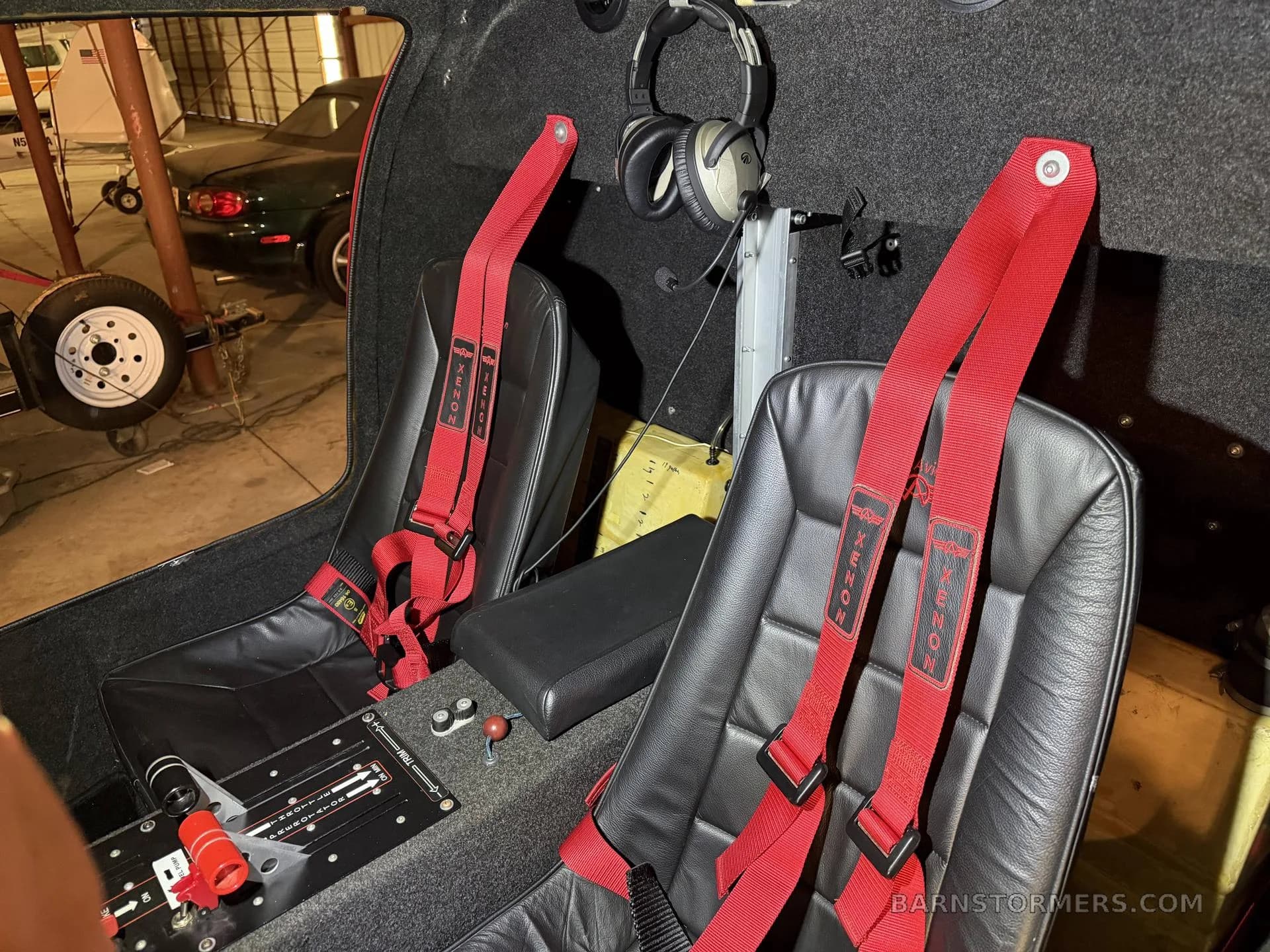 The interior of a red autogyro shows two black leather seats with red "Xenon" branded harnesses and a central console.