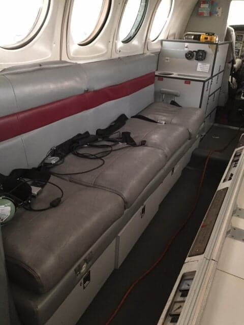 A view of the interior of the aircraft, showing a bench seat and storage area.