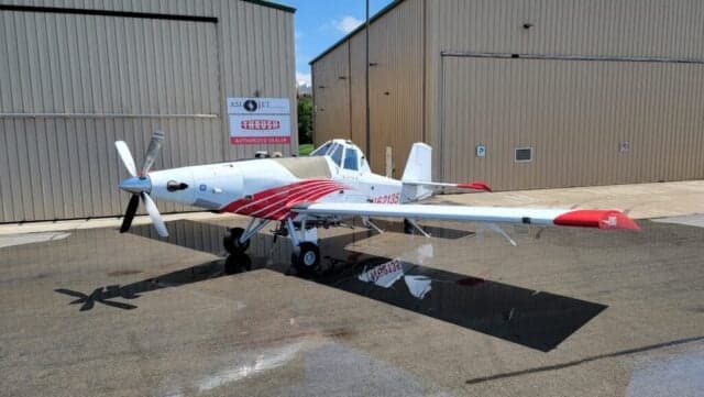 A Thrush 510G aircraft with a white and red paint scheme is parked on the tarmac.