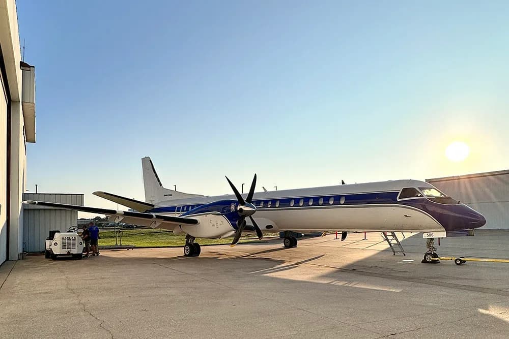 Side view of a blue and white aircraft parked on the tarmac.