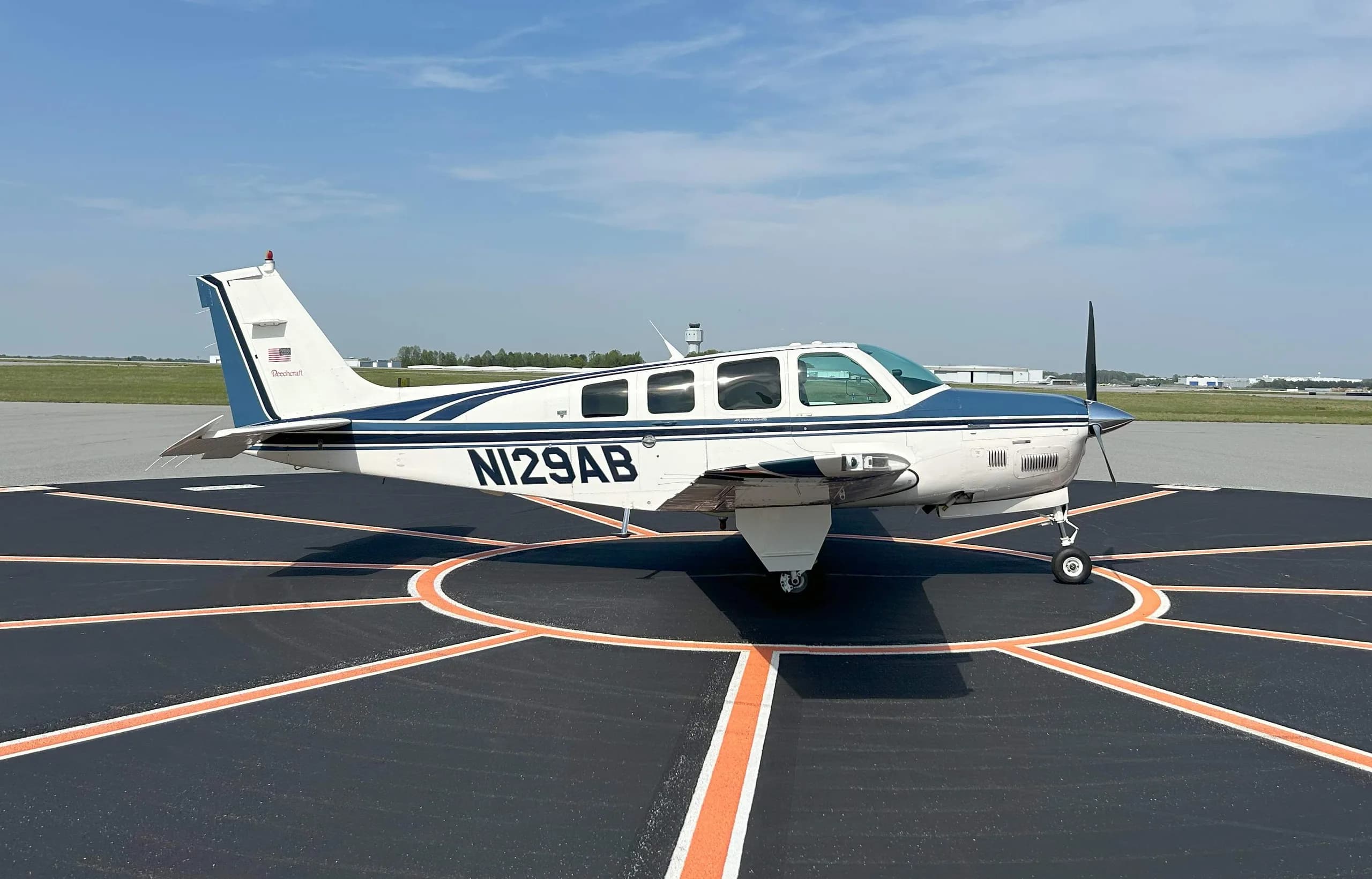 Beechcraft Bonanza with white and blue paint scheme on a tarmac.