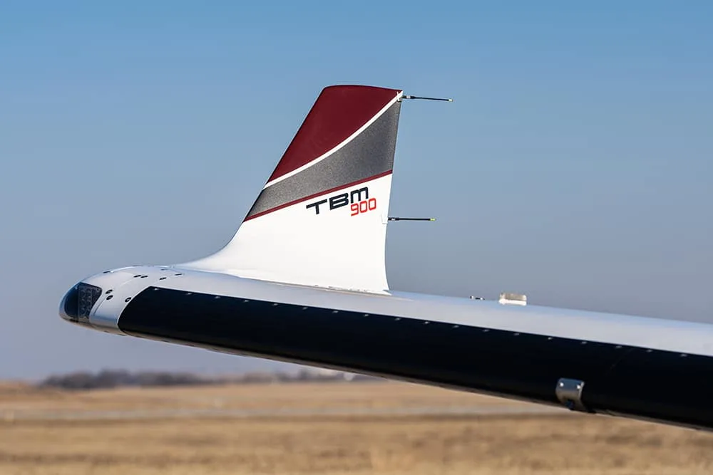 Close-up of the tail of a Daher TBM 900 aircraft, showing the "TBM 900" logo on the vertical stabilizer.