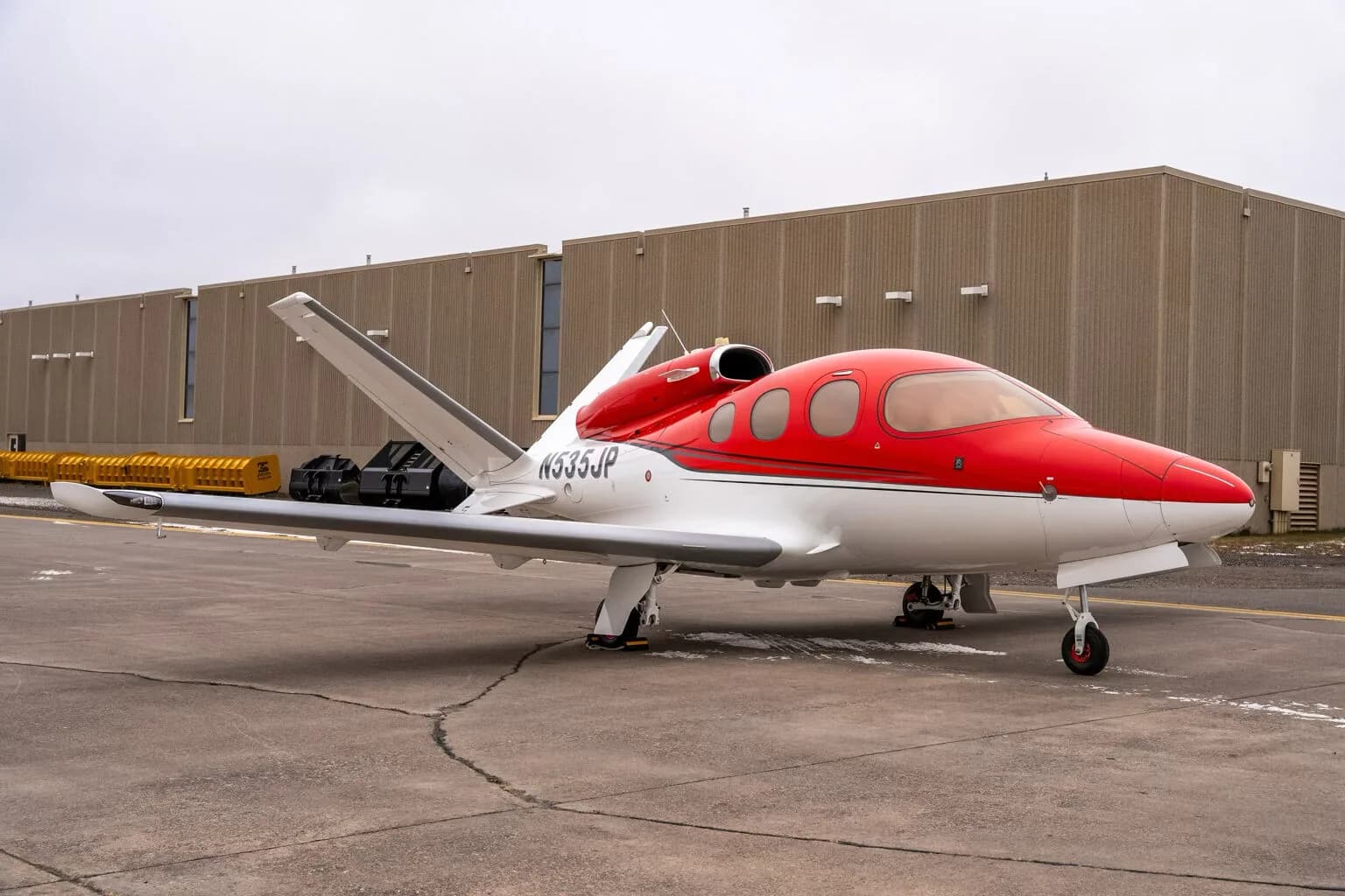 Front right view of a red and white Cirrus Vision Jet (N535JP) on the tarmac.