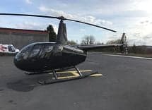 Side view of a black Robinson helicopter on the tarmac.