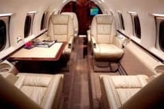 The interior of an aircraft with leather seats and a table.