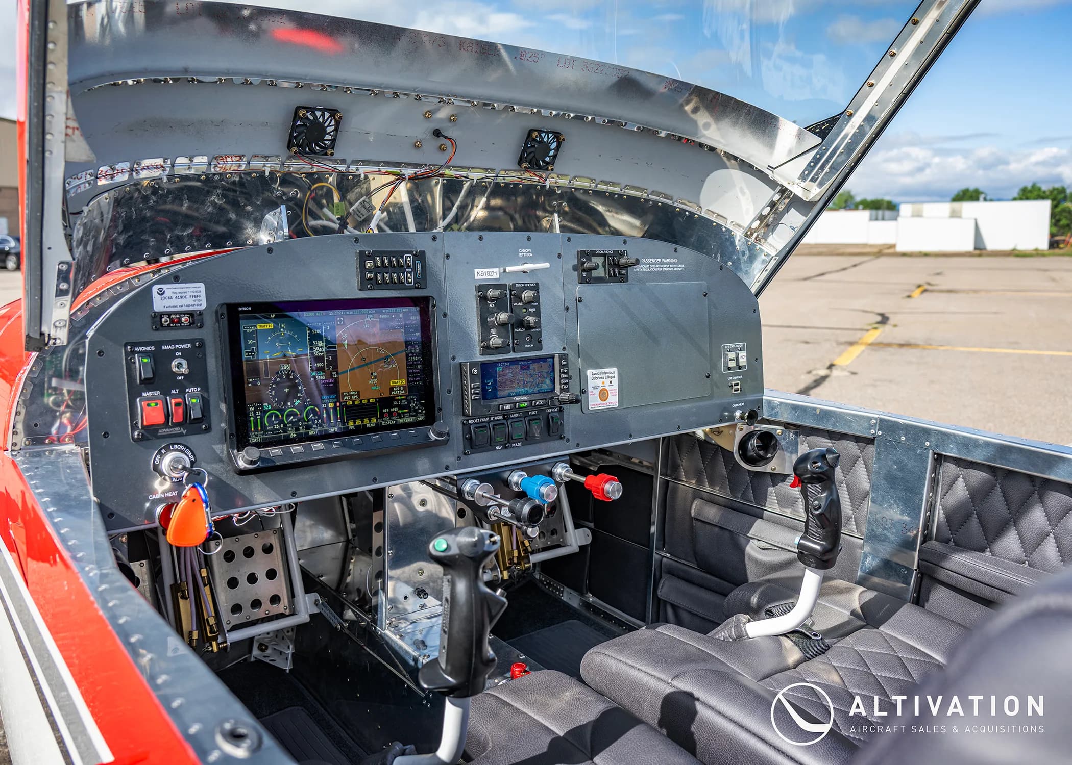 The cockpit of a red and white experimental aircraft, showing modern glass panel displays and flight controls.