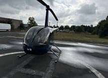 A blue Robinson R44 helicopter on a helipad, viewed from the front.