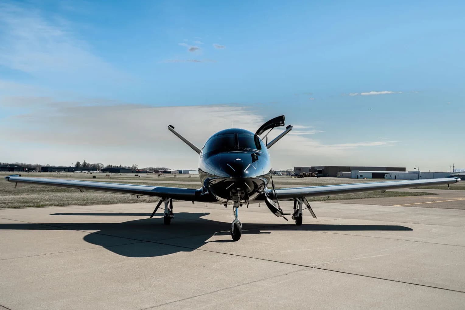Front view of a black Cirrus Vision Jet (N71AB) parked on an airport tarmac with its main door open.