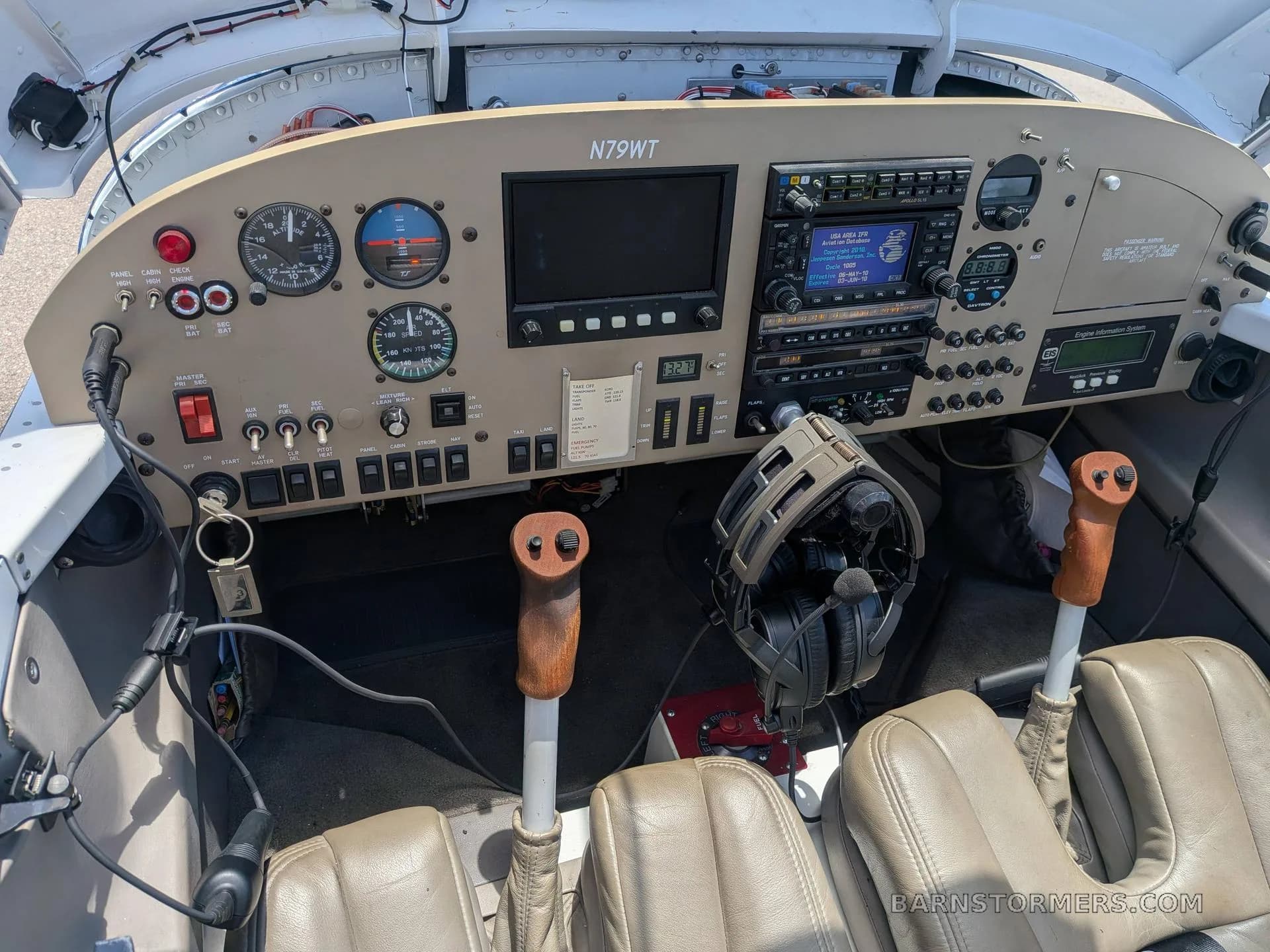 The cockpit of an experimental aircraft (N79WT) features a beige instrument panel with a mix of analog gauges and digital displays, two control sticks, and tan leather seats.