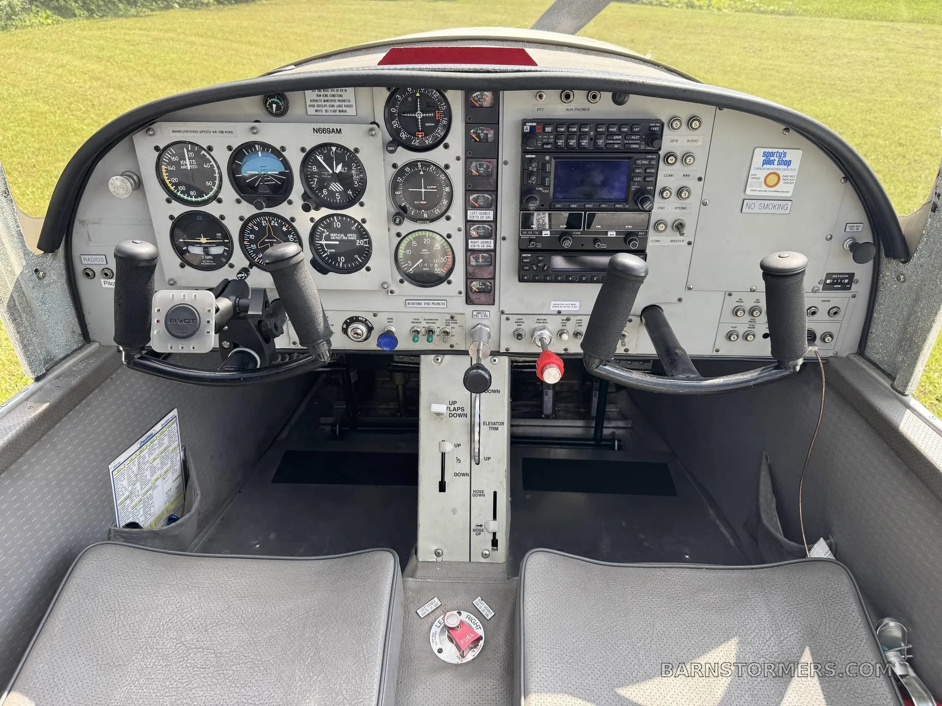 The cockpit of a small aircraft, showing the instrument panel, dual yokes, and center console with throttle and flap controls.