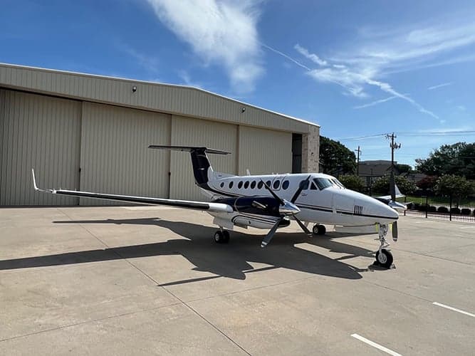 King Air aircraft N711VN parked on the tarmac in front of a hangar.