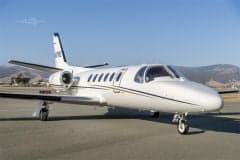 A Cessna Citation CJ1+ aircraft on the tarmac with a clear blue sky in the background.