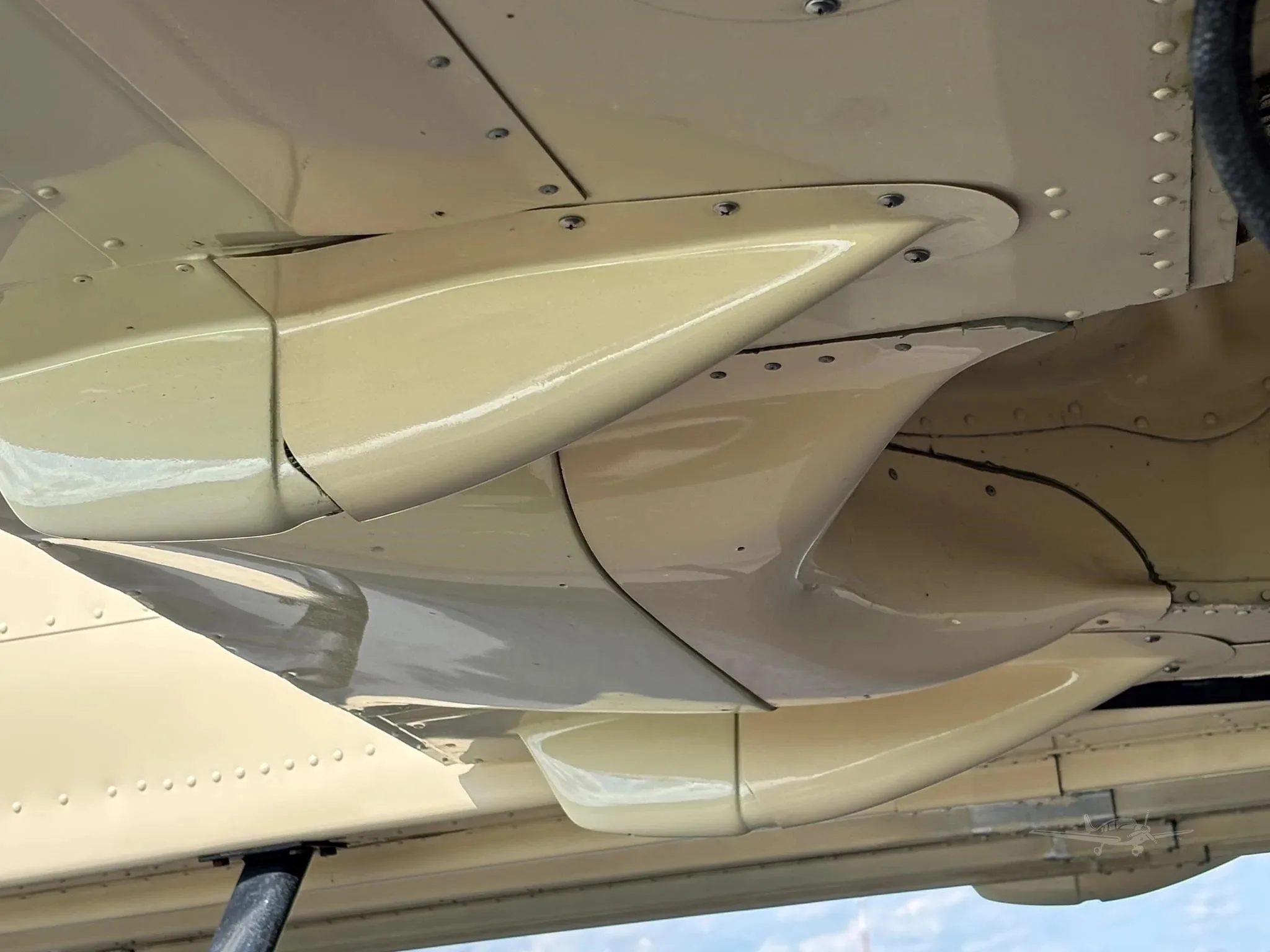 A close-up view of the beige underside of the aircraft's wing and fuselage.