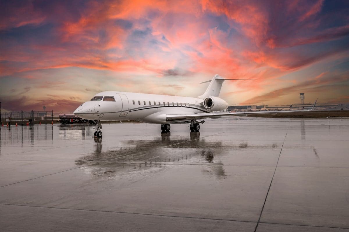 Front view of a white Bombardier Global Express on a wet tarmac.
