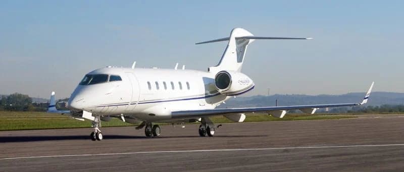 A white and blue Bombardier Challenger parked on the tarmac.