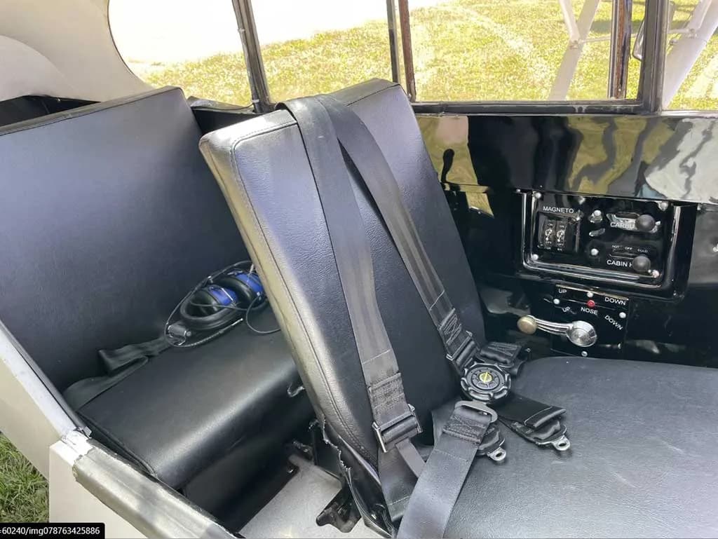 The black leather seats and seatbelts in the aircraft's cabin, with a headset on the rear seat.