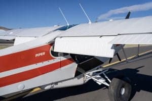 Close-up of the wing and fuselage of a Piper Super Cub aircraft with a red and white paint scheme.