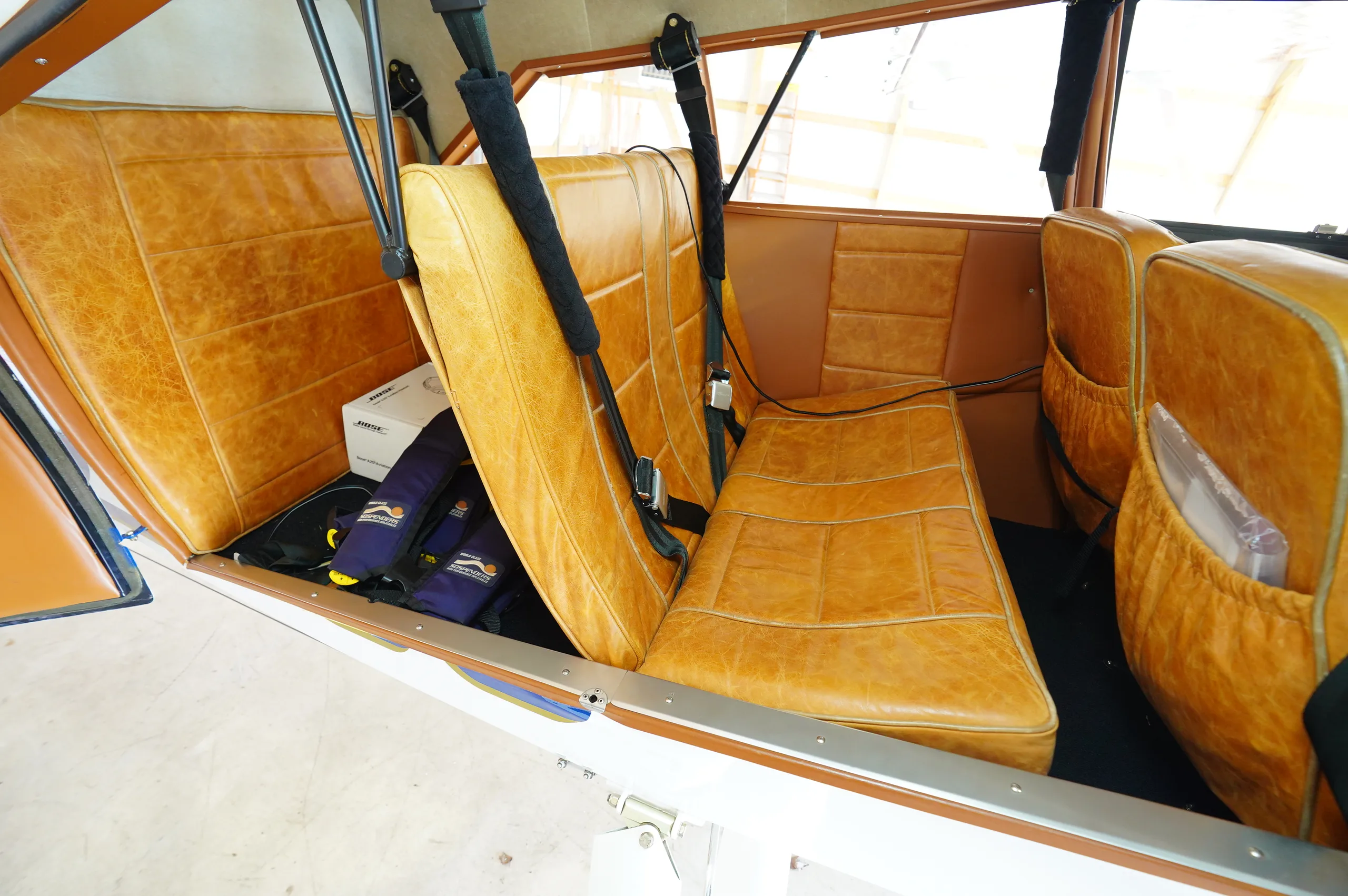 The tan leather seats in the aircraft's cabin, with life vests visible.