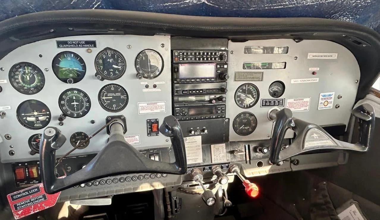 The aircraft cockpit showing the instrument panel with gauges, radios, and dual control yokes.