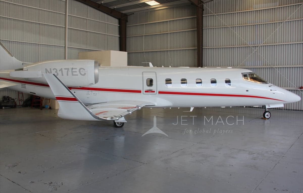 Side view of the N317EC aircraft in a hangar, showing its white paint scheme with red stripes.