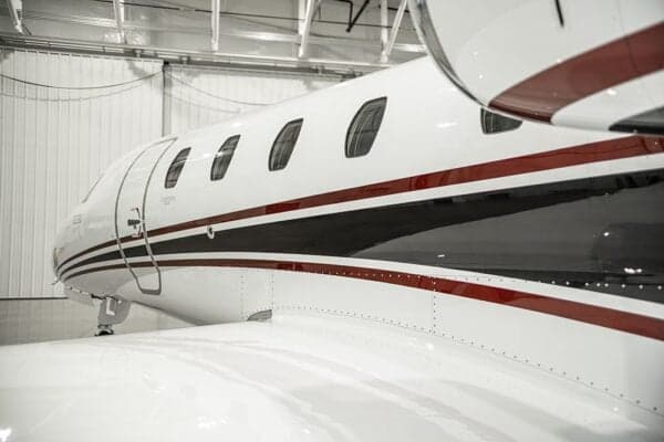 A close-up of the fuselage of a Citation jet with a white and red paint scheme.