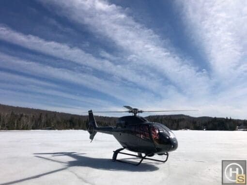 An Airbus helicopter, registration C-FMTJ, is parked on a frozen lake.