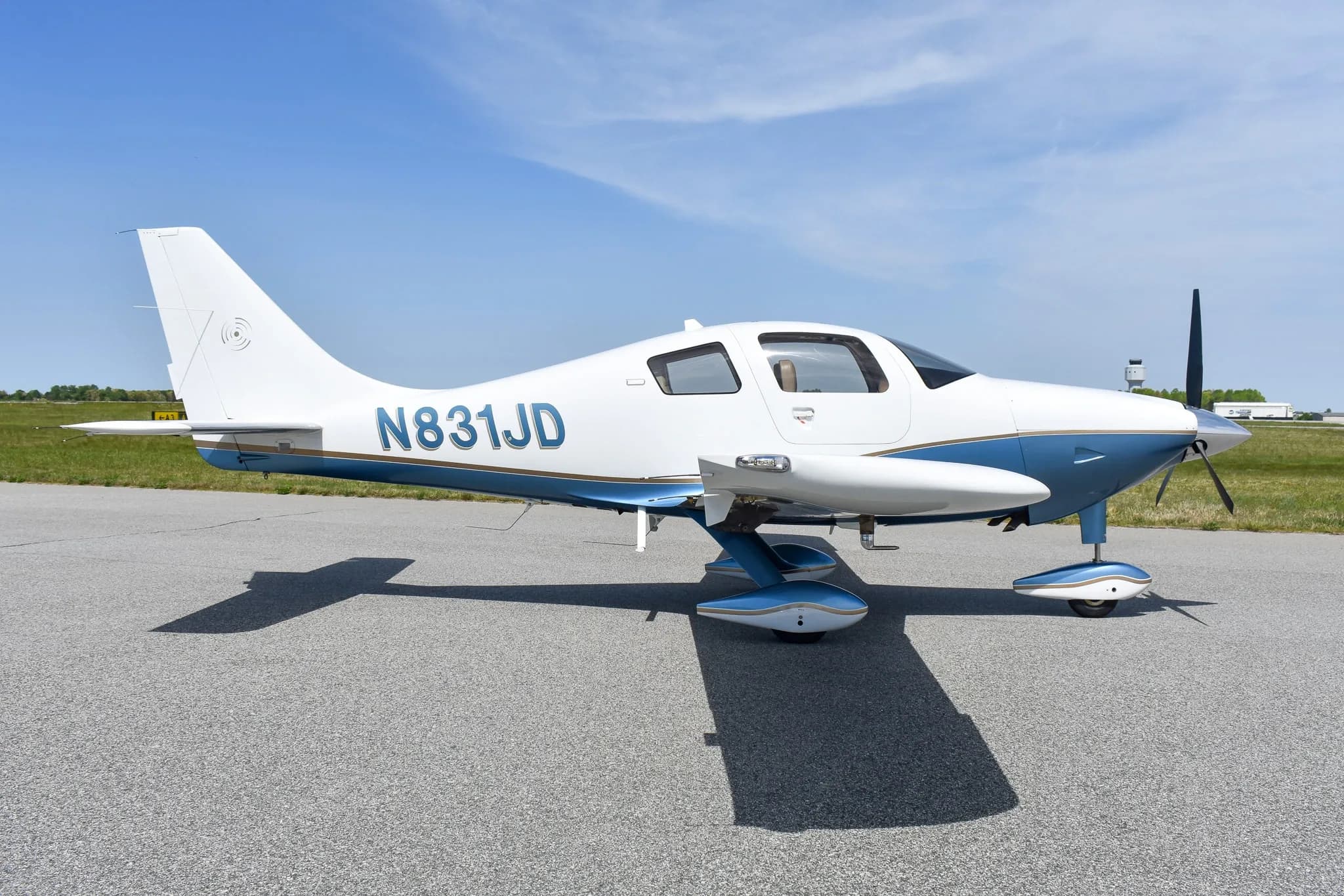 Side view of a white and blue single-engine aircraft with registration N831JD parked on an airfield.