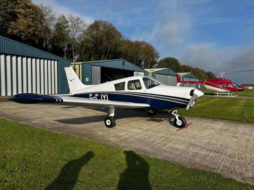 Piper PA-28-161 Warrior II aircraft on the ground in front of hangars.