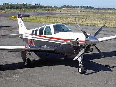 A Beechcraft Bonanza on the tarmac with a gray and white paint scheme.