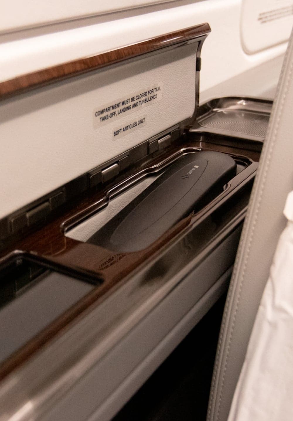 Close up of an aircraft interior compartment with a phone inside.