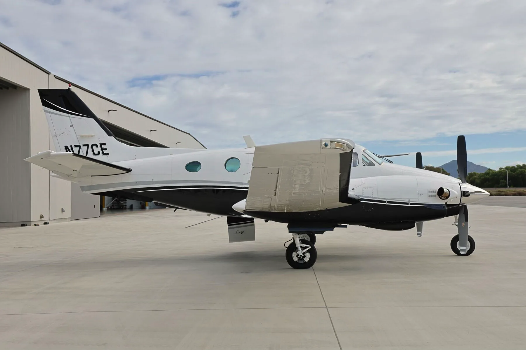 A left side view of the N77CE twin-engine turboprop aircraft with its flaps extended.