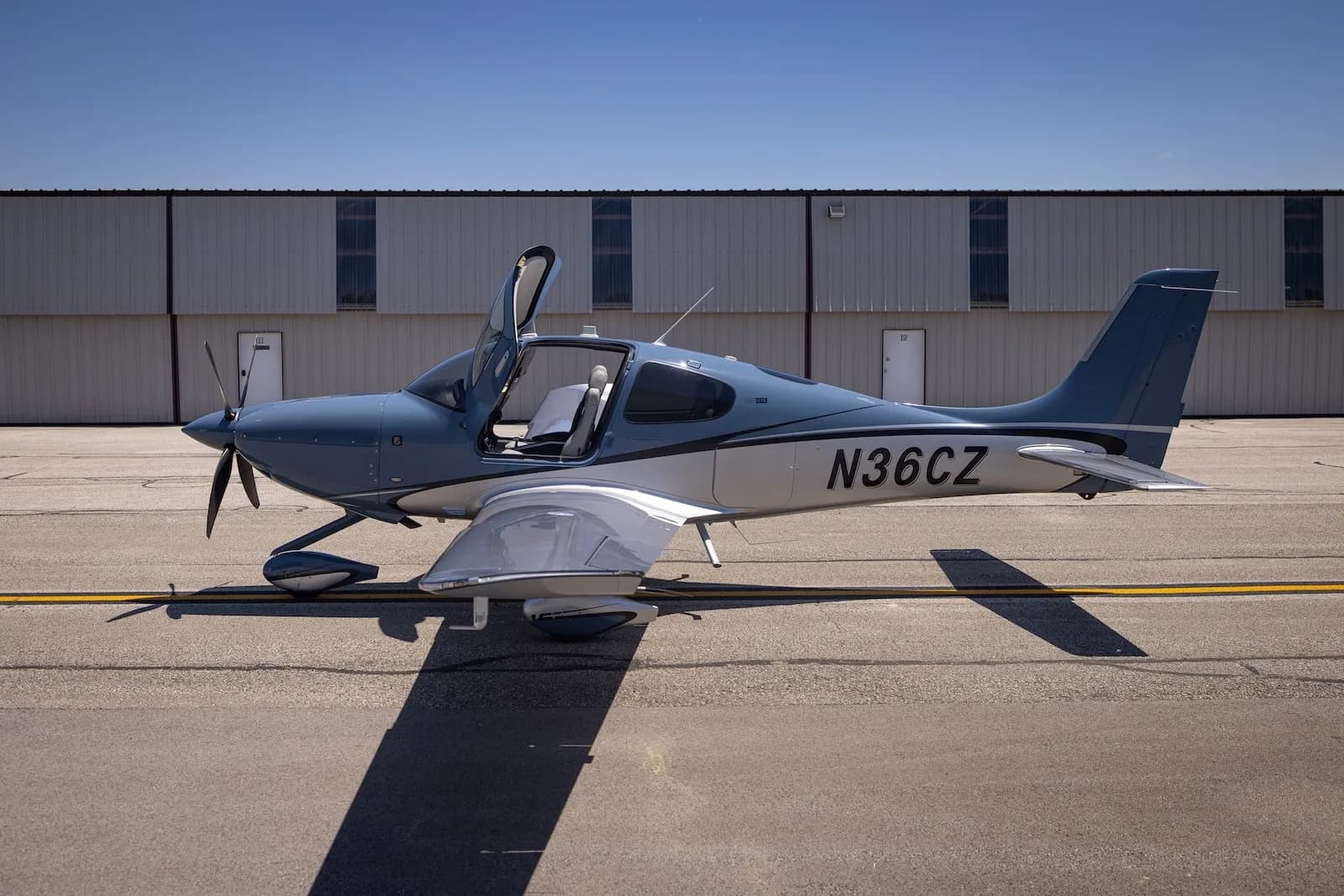 A Cirrus SR22T aircraft with open doors is parked on the tarmac.