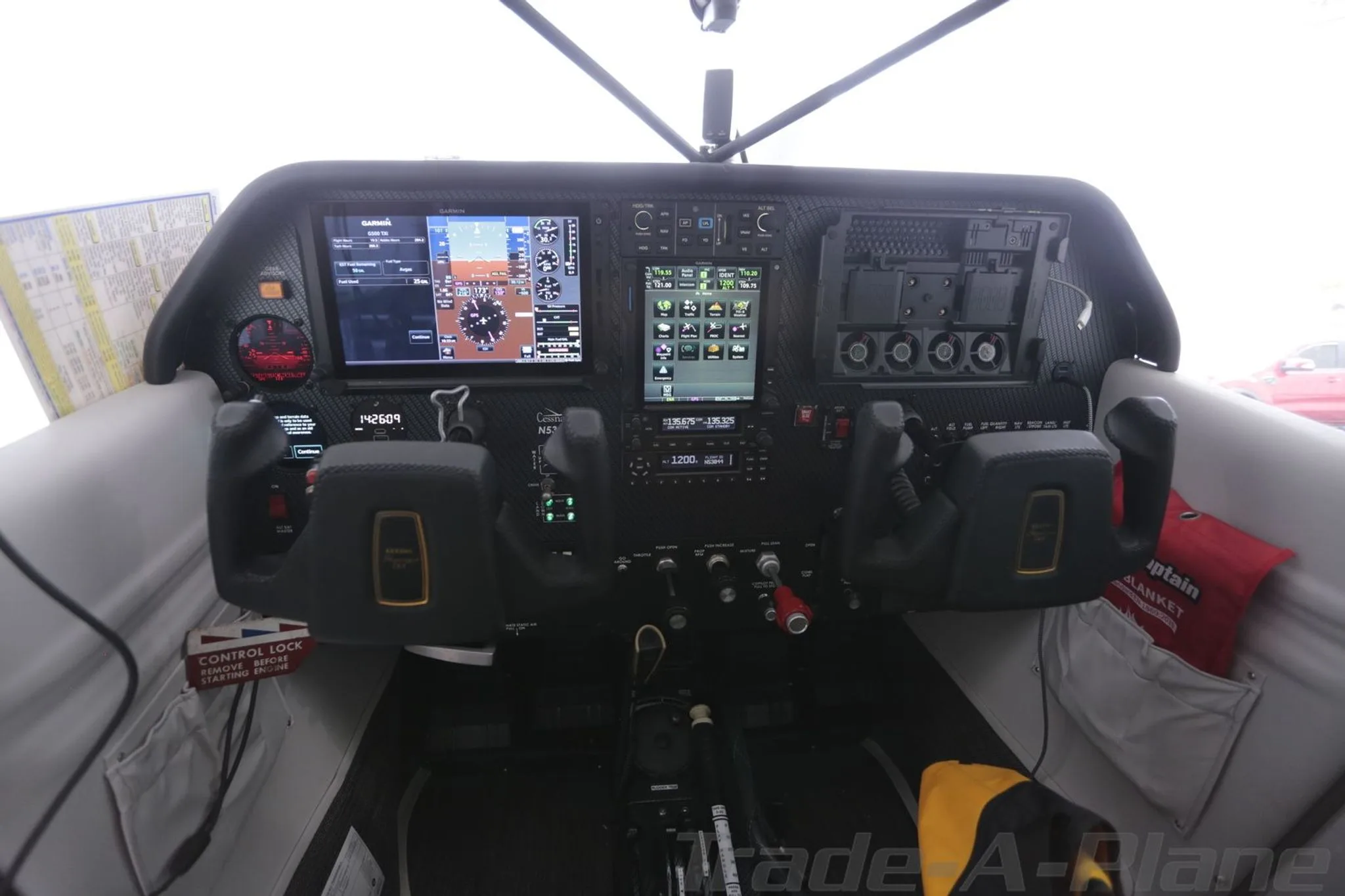 The cockpit of a Cessna 180 Skywagon, featuring a modern glass panel with two large displays and yokes.
