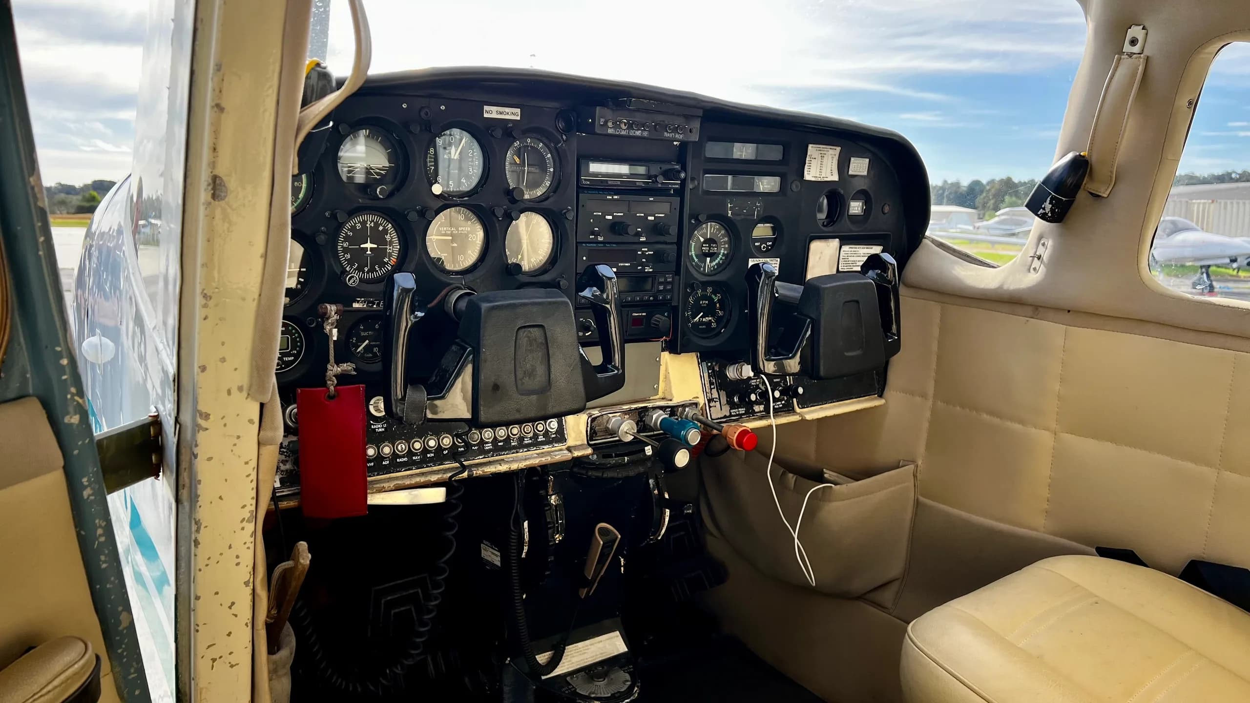 The cockpit of a single-engine aircraft, showing the instrument panel with analog gauges and dual yokes.