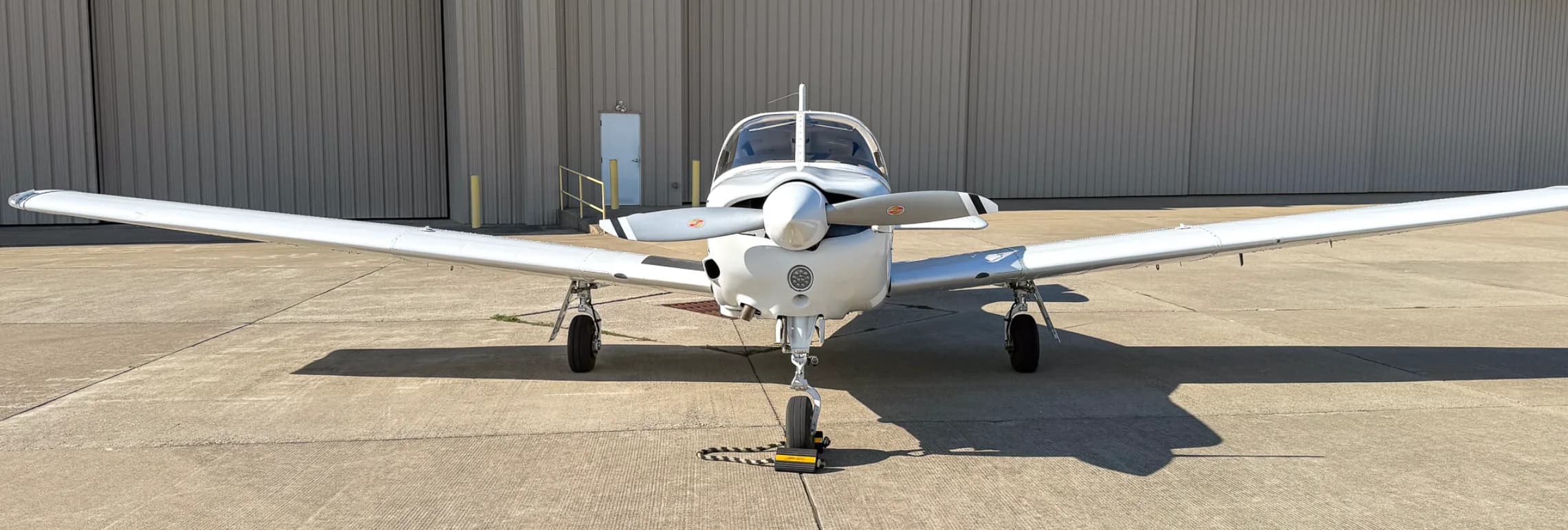 A head-on view of the white Piper Arrow III aircraft, tail number N751KS, parked on an airport tarmac.