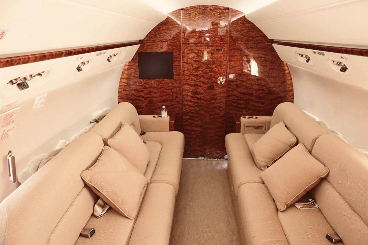 The interior of the aircraft features tan couches and wood paneling.