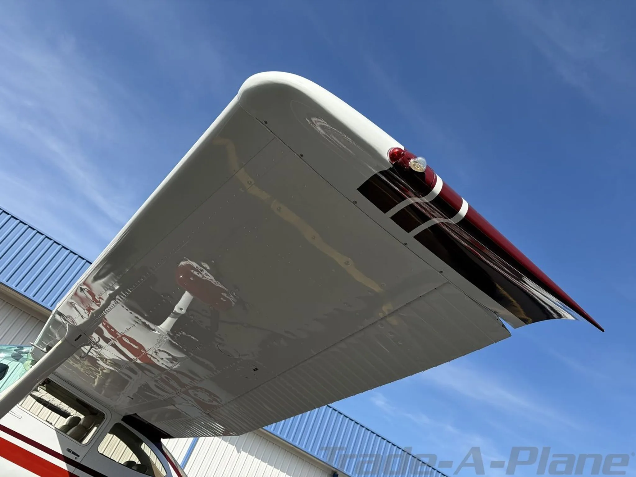 An upward view of the underside of the right wingtip of the white and red Cessna Skylane II.
